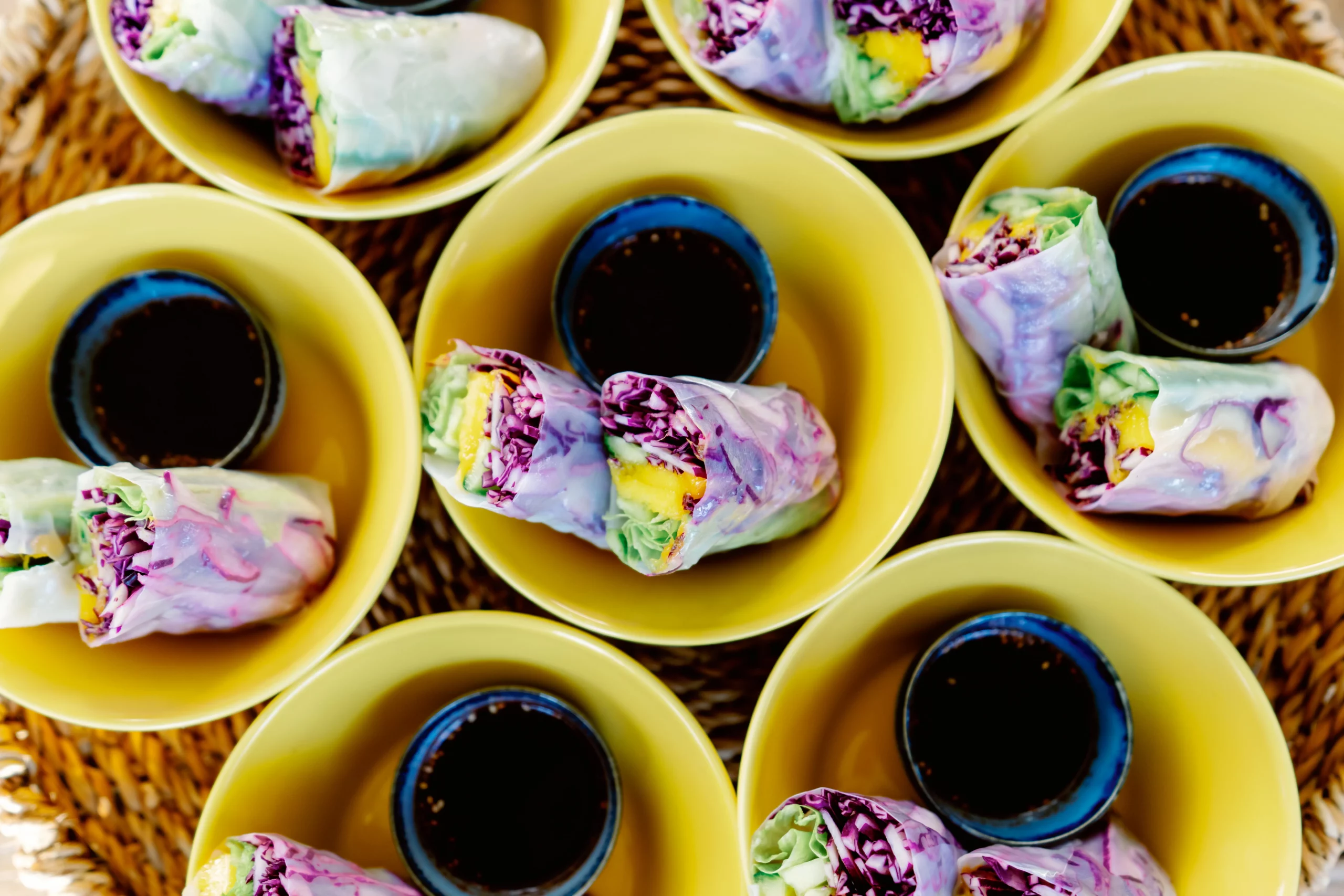 Fresh and colorful plant-based rice paper spring rolls served in bright yellow bowls with a dipping sauce at the Seeds of Silence wellness retreat in Algarve, Portugal.
