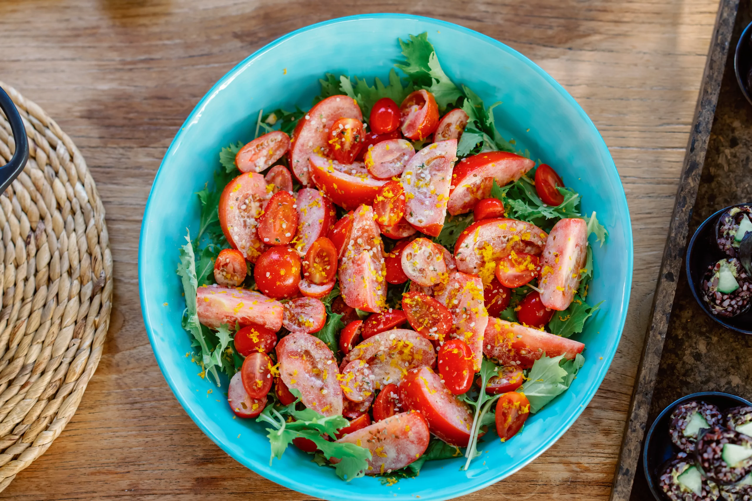 A close-up of a fresh, vibrant salad with sliced tomatoes, green herbs, and wholesome ingredients served in a bright blue ceramic bowl at the Seeds of Silence wellness retreat in Algarve, Portugal.