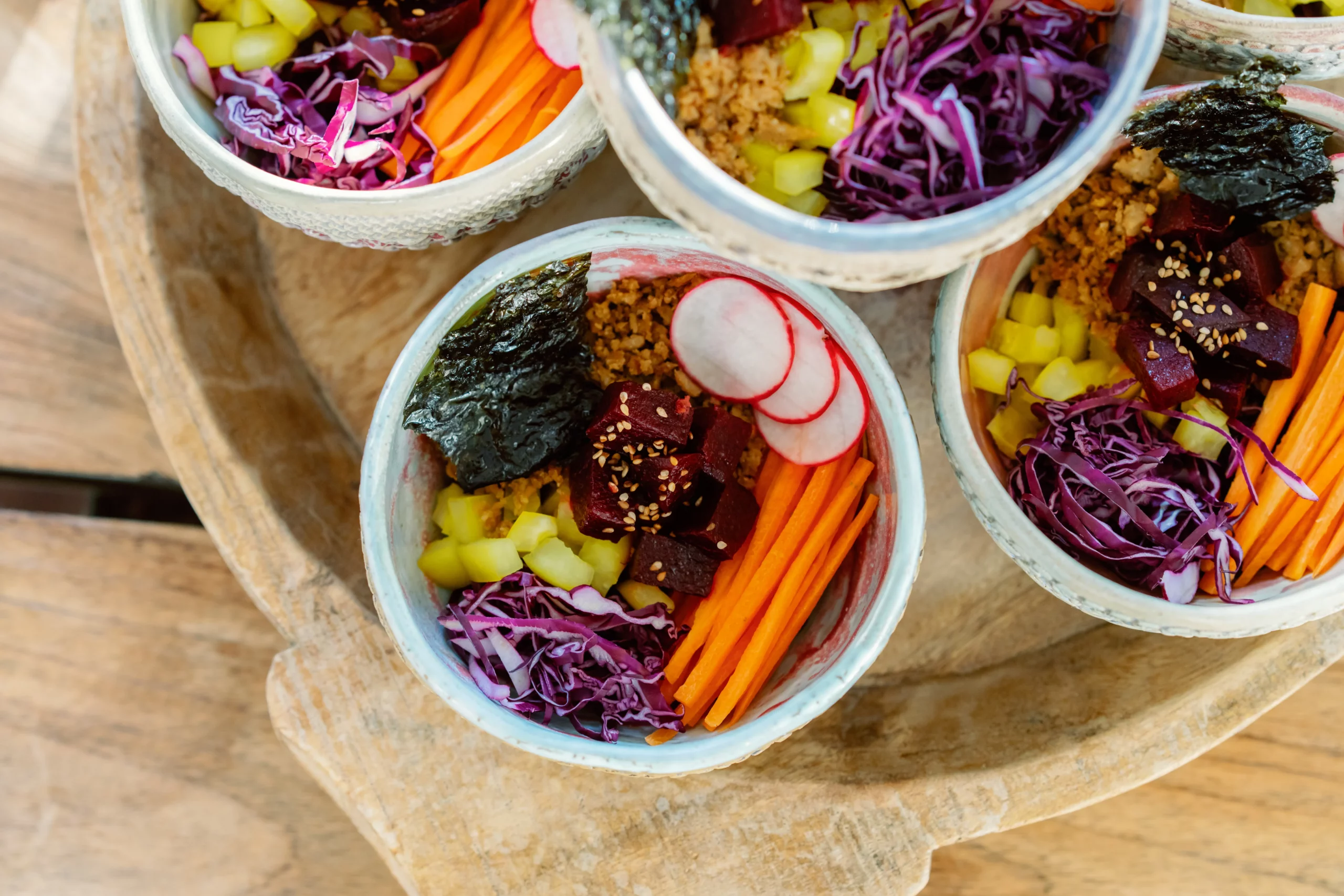 Gallery, Healthy individual Buddha bowls packed with vibrant purple cabbage, shredded carrots, greens, and grains served at the Seeds of Silence wellness retreat in Algarve, Portugal.