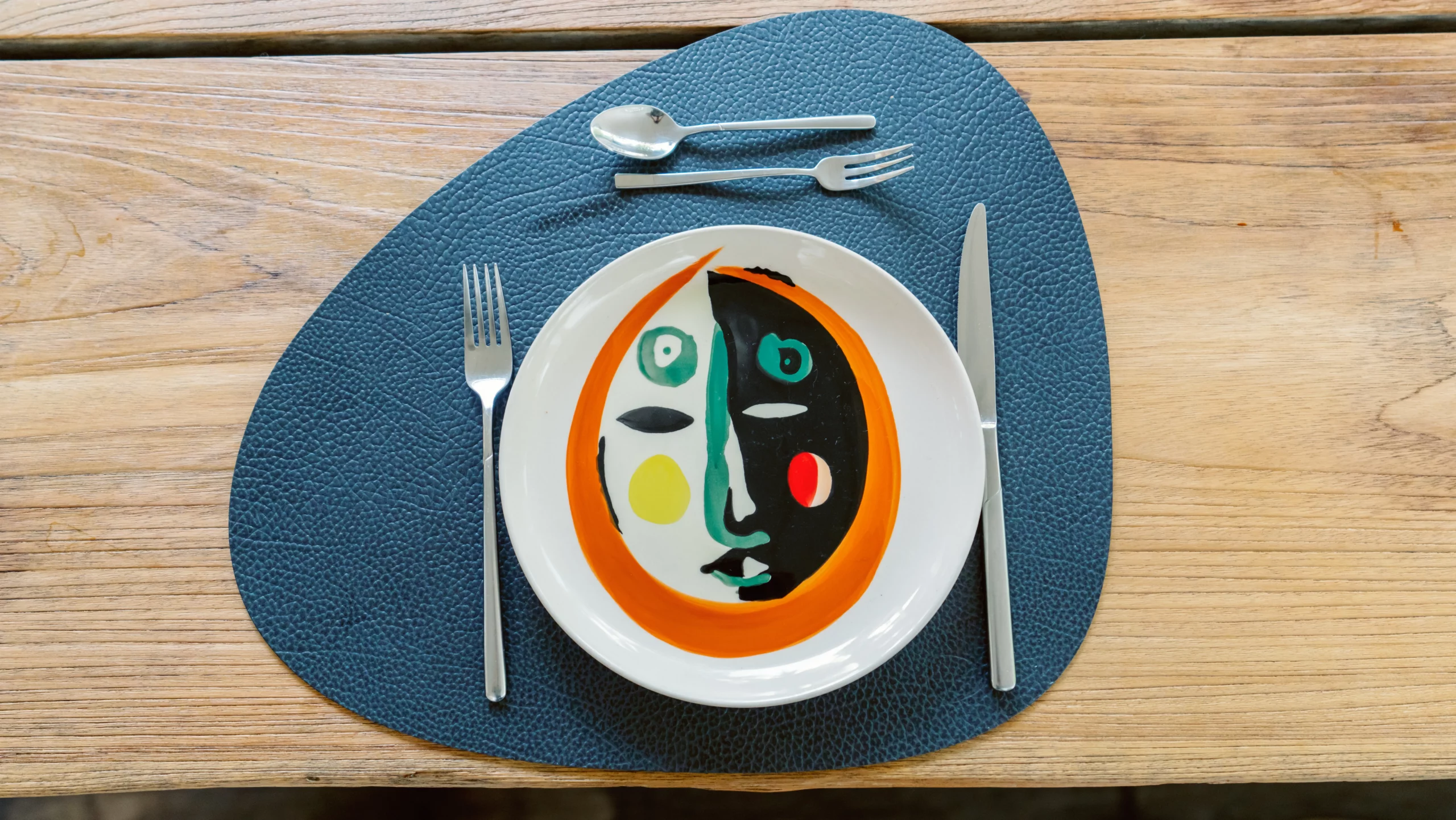A top-down view of a healthy plant-based dish beautifully served on an orange and white patterned plate with a blue placemat at the Seeds of Silence wellness retreat in Algarve, Portugal.