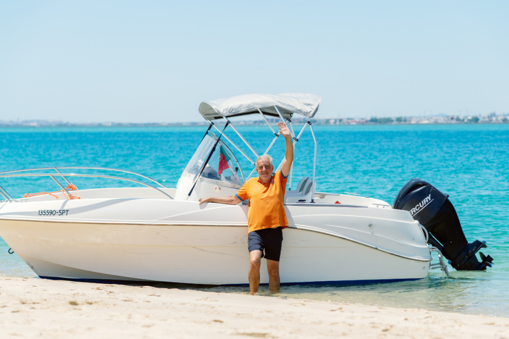 A woman waving from a small boat on the crystal-clear azure sea during an island hopping excursion in the Algarve.